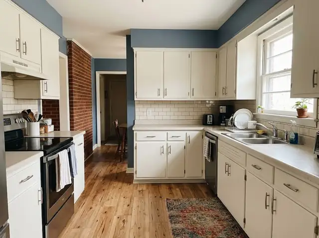 Small updated kitchen with white painted cabinets, plank flooring and a slate blue wall