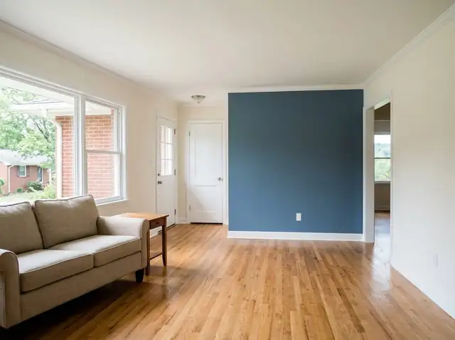 Freshly painted living room with white trim and a slate blue accent wall