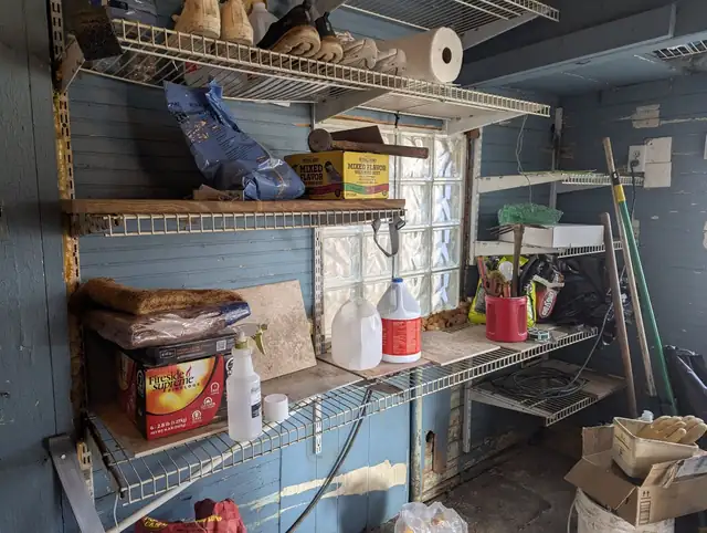 Before: cluttered basement entry room with blue-gray walls and wire shelving full of stored items