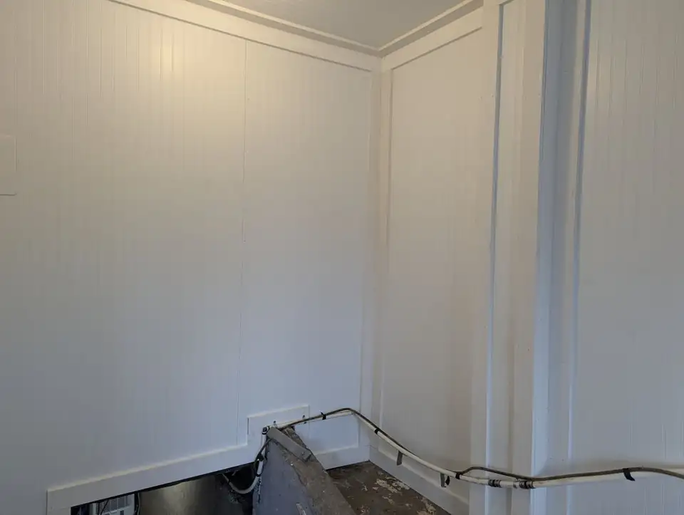 Basement entry room finished in white paneling with crown trim and a handrail, home repairs and remodeling Knoxville TN